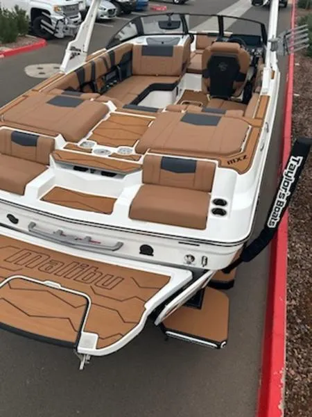 Slide: The Image of 2025 Malibu 22 MXZ boat with tan and black interior, docked on pavement. - 6