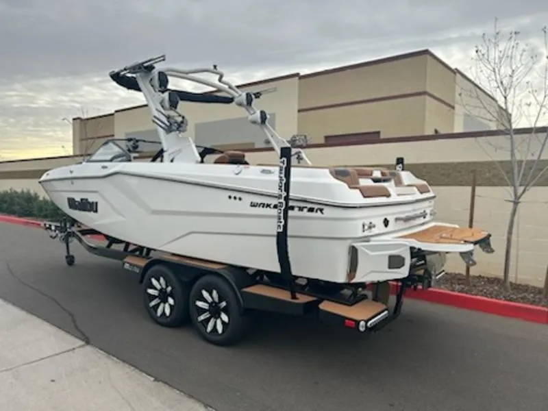 Slide: The Image of 2025 Malibu 22 MXZ boat on trailer, parked outdoors, showcasing sleek design and modern features. - 9
