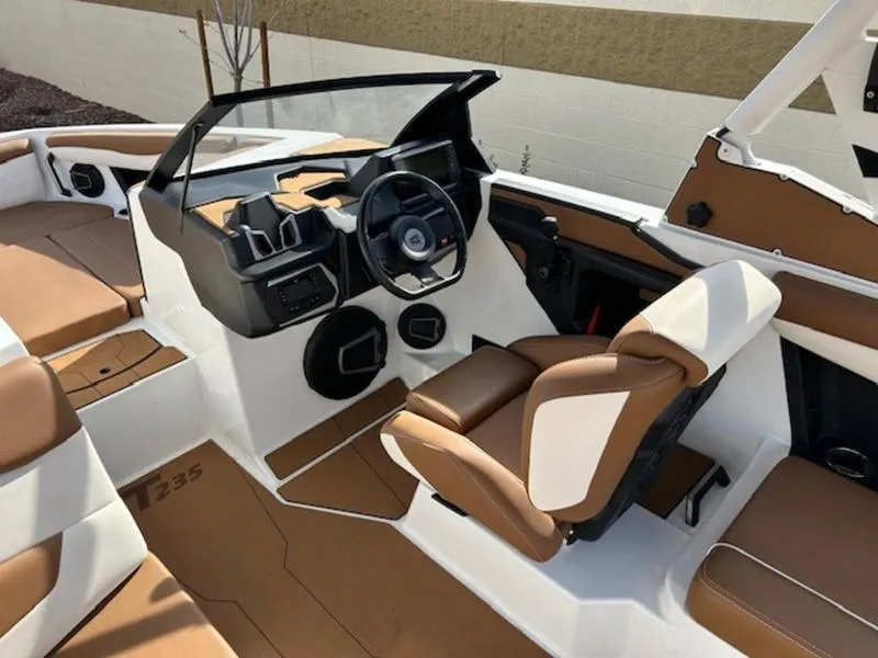 Slide: The Image of 2024 Axis T235 boat interior with brown and white seating, modern dashboard, and steering wheel. - 16