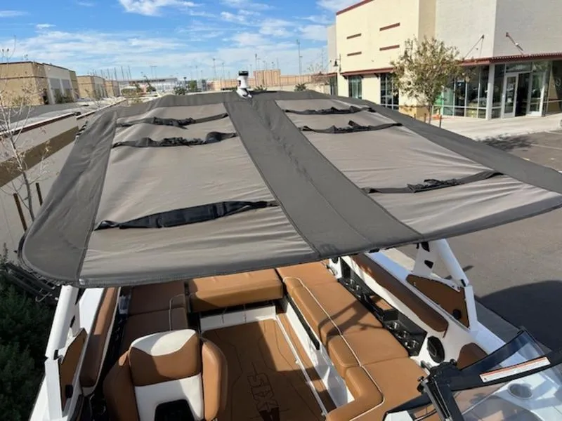 Slide: The Image of 2024 Axis T235 boat with sunshade canopy, brown seating, parked outdoors. - 19