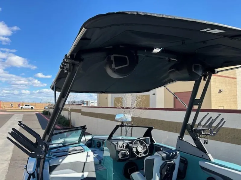 Slide: The Image of 2024 Axis T250 boat interior with speakers and wakeboard racks under a sunny sky. - 11