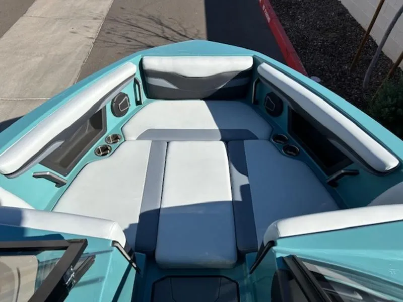 Slide: The Image of 2024 Axis T250 boat interior with teal and gray seating, cup holders, and speakers. - 15