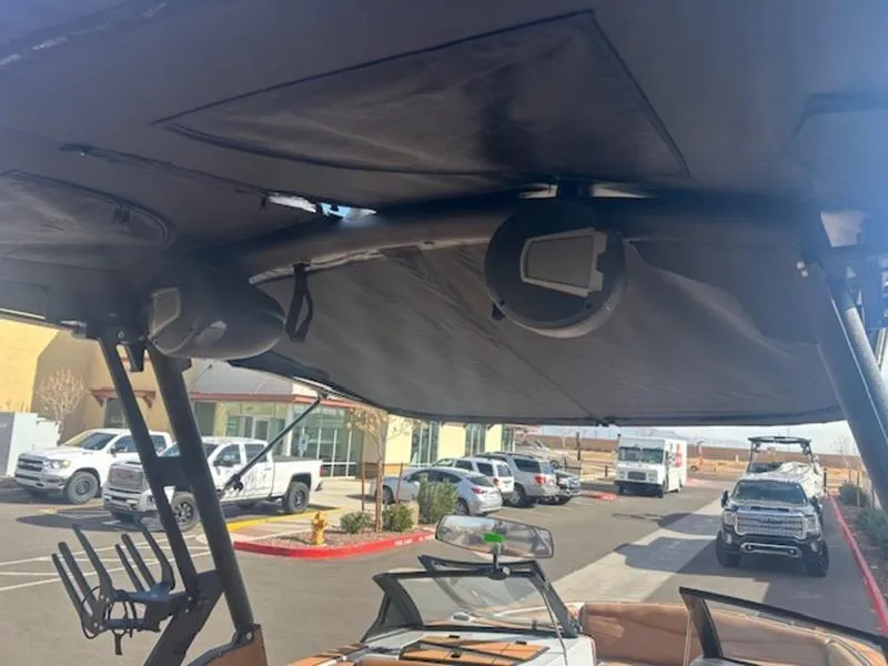 Slide: The Image of 2025 Axis A225 boat interior with speakers and parked vehicles in background. - 10