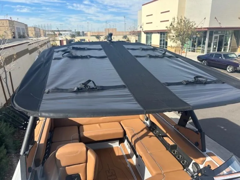 Slide: The Image of 2025 Axis A225 boat with tan seating and black canopy in a parking lot. - 21