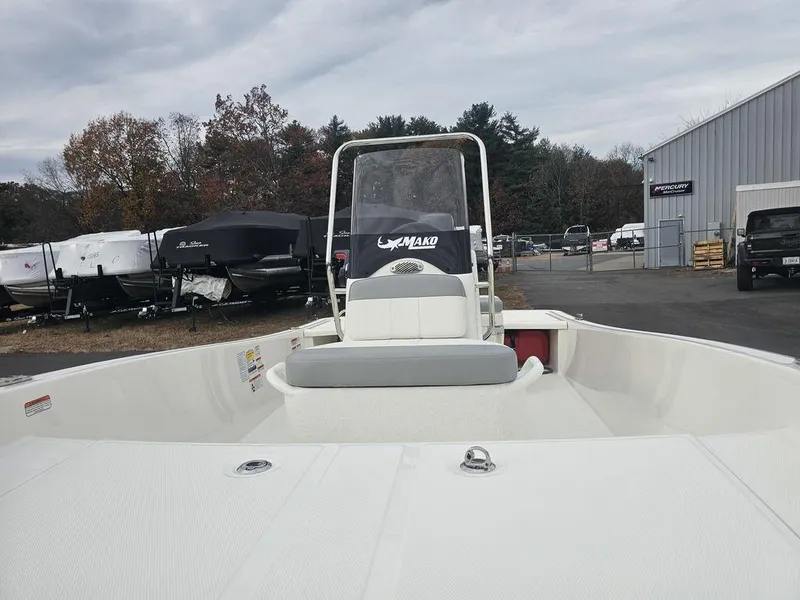 Slide: The Image of 2025 Mako Pro Skiff 15 CC boat in a marina, surrounded by trees and buildings. - 18