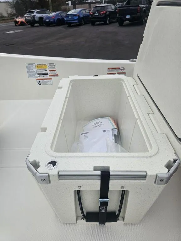 Slide: The Image of 2025 Mako Pro Skiff 15 CC boat storage compartment with latch, parked cars in background. - 33