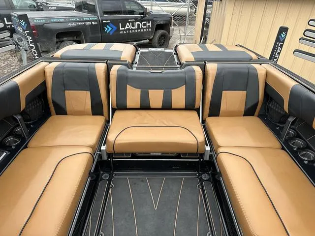 Slide: The Image of 2023 Malibu 23 LSV boat interior with tan and black seating, showcased by Launch Watersports. - 10
