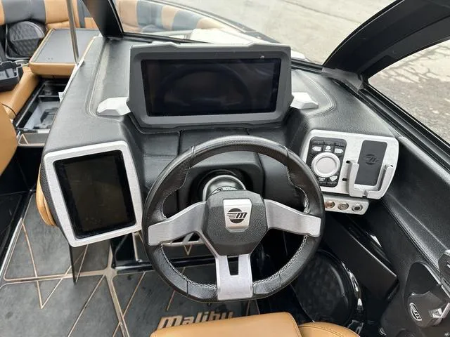 Slide: The Image of 2023 Malibu 23 LSV boat dashboard with modern steering and digital displays. - 11