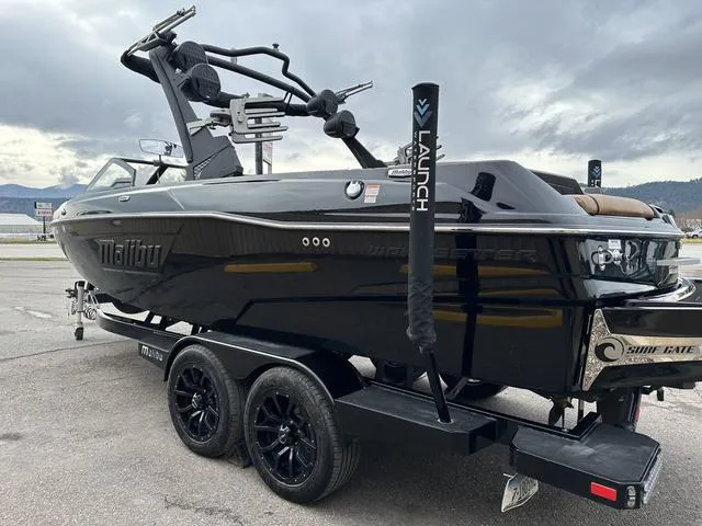 Slide: The Image of 2023 Malibu 23 LSV boat on trailer, sleek black design, overcast sky background. - 5