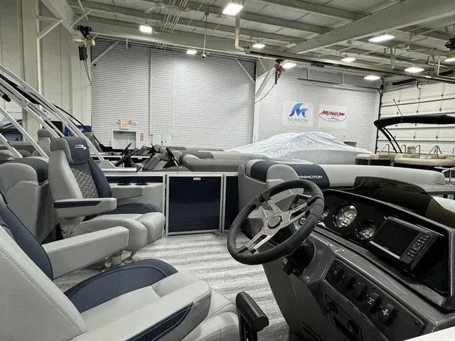 Slide: The Image of 2025 Bennington 23 SSR pontoon boat interior in showroom, featuring modern dashboard and seating. - 8