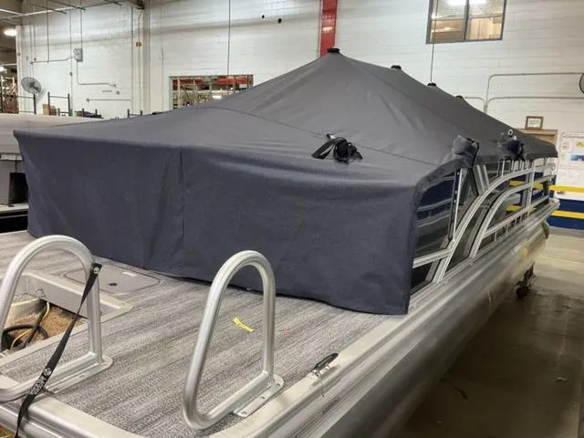Slide: The Image of 2025 Bennington 23 SSB pontoon boat with cover in a warehouse setting. - 16