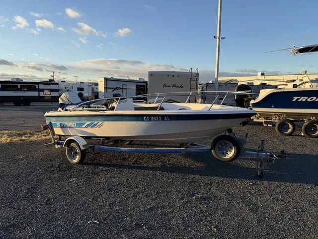 Slide: The Image of 1990 Sunbird 15SW boat on trailer in parking lot, clear sky background. - 1