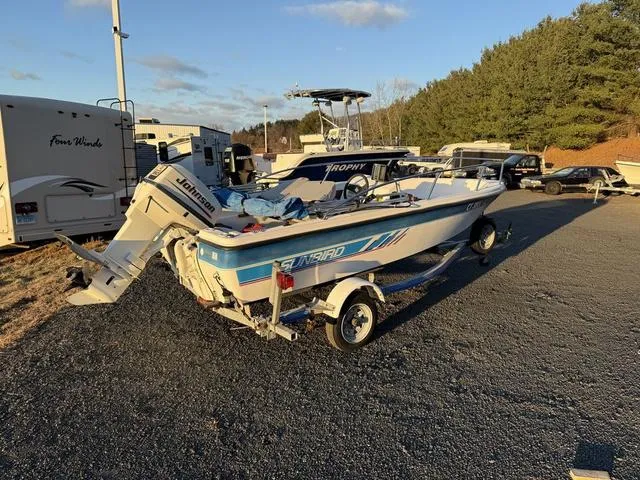 Slide: The Image of 1990 Sunbird 15SW boat with Johnson outboard motor on trailer, parked outdoors. - 2