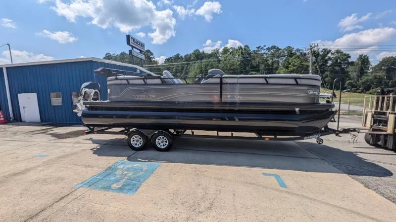 The Image of 2025 Regency 250 LE3 pontoon boat on trailer, parked outside dealership. - 0