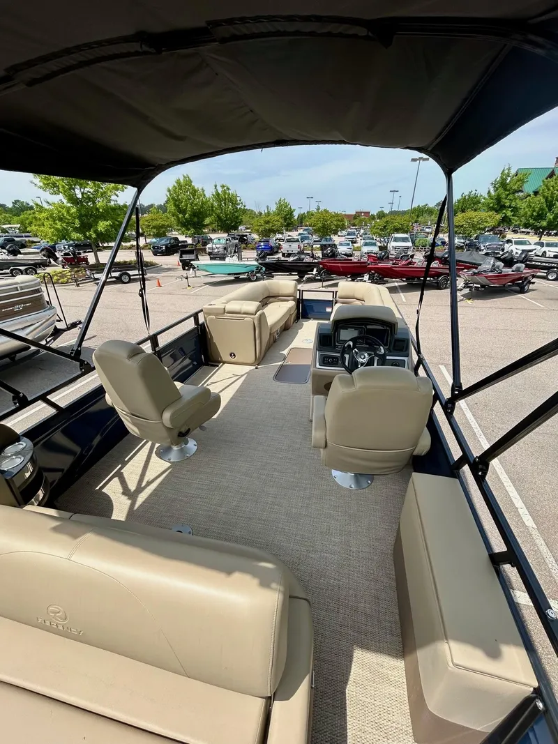 Slide: The Image of 2025 Regency 250 DL3 pontoon boat interior with beige seating and steering console. - 2