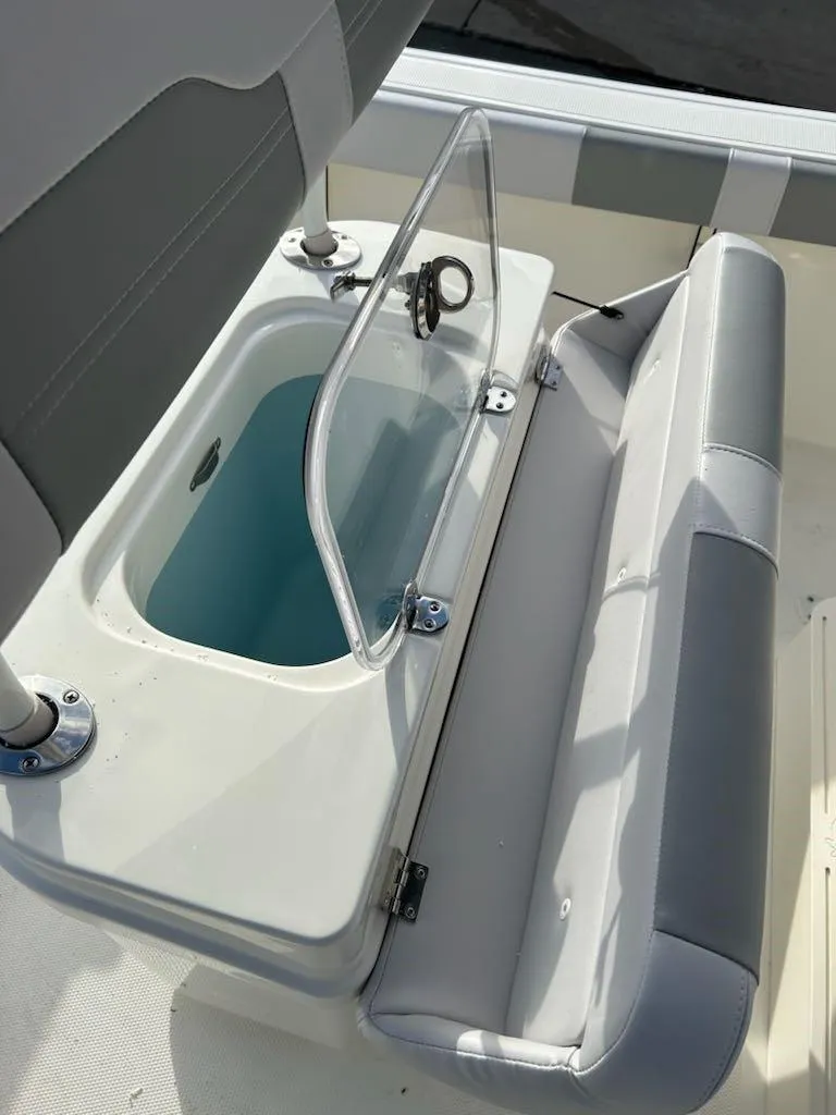 Slide: The Image of 2025 Mako 214 CC boat with open storage compartment and cushioned seating. - 3