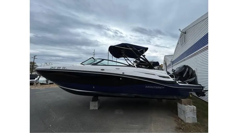 Slide: The Image of 2018 Monterey M65 boat on blocks, parked outdoors under cloudy sky. - 1