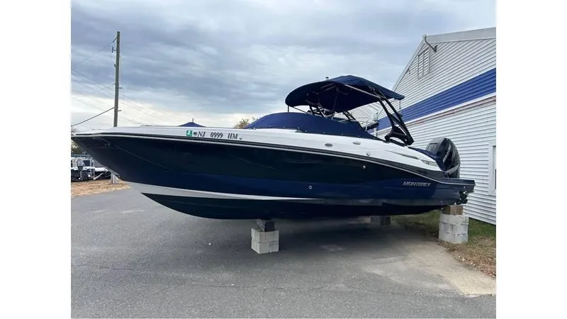 Slide: The Image of 2018 Monterey M65 boat on blocks, dark blue hull, parked outdoors. - 3