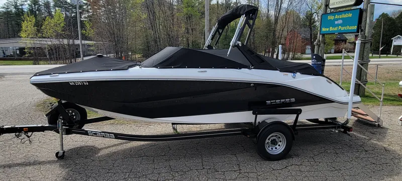 Slide: The Image of 2021 Scarab 215 ID boat on trailer, black and white design, parked outdoors. - 2