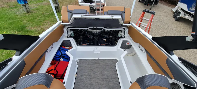 Slide: The Image of 2021 Scarab 215 ID boat interior with open engine compartment, tan and gray seating. - 21