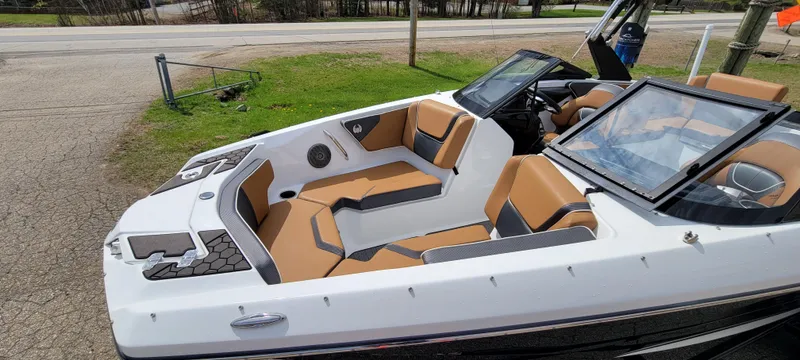 Slide: The Image of 2021 Scarab 215 ID boat with tan and black interior, parked on a driveway. - 6