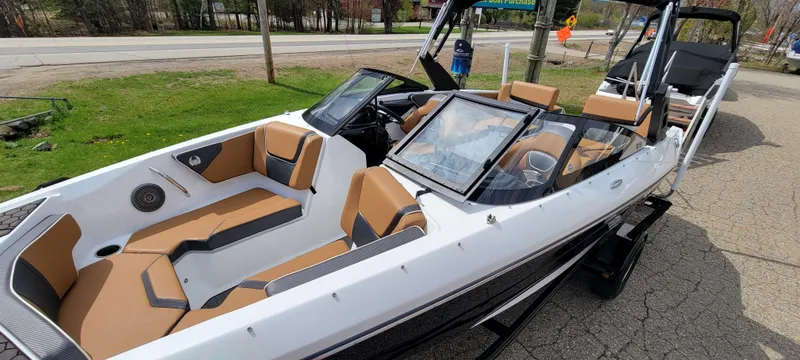 Slide: The Image of 2021 Scarab 215 ID boat with tan and black interior, parked on a driveway. - 8