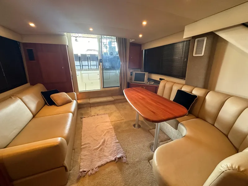 Slide: The Image of Interior of 2002 Silverton 35 Convertible yacht with beige seating and wooden table. - 17