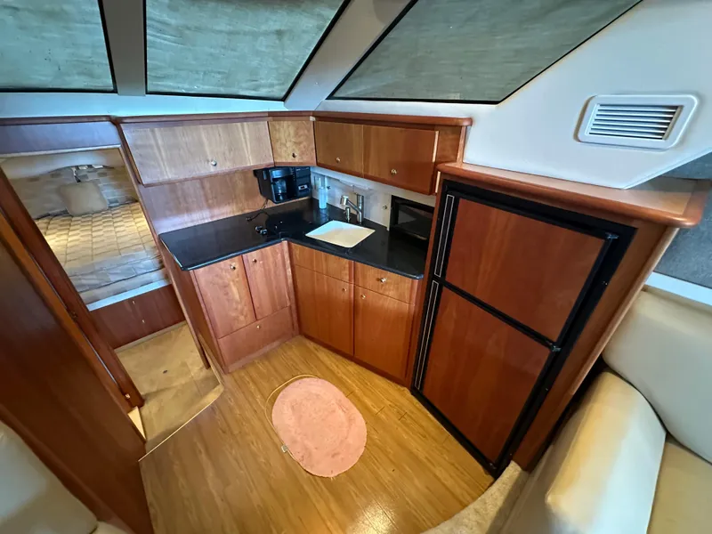 Slide: The Image of Interior of 2002 Silverton 35 Convertible yacht kitchen with wood cabinetry and black countertops. - 21
