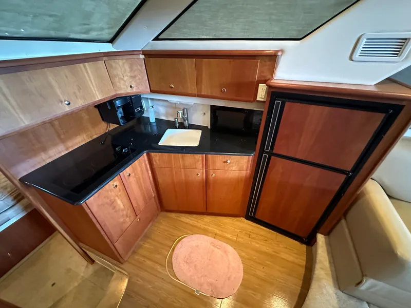 Slide: The Image of 2002 Silverton 35 Convertible yacht kitchen with wood cabinets and black countertops. - 22