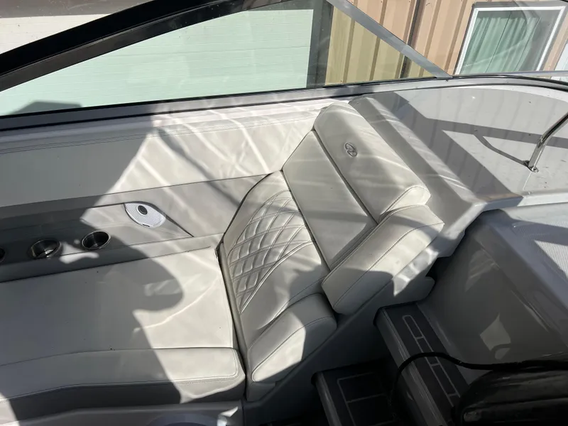 Slide: The Image of 2021 Regal 28 Express boat interior with white leather seating and cup holders. - 22