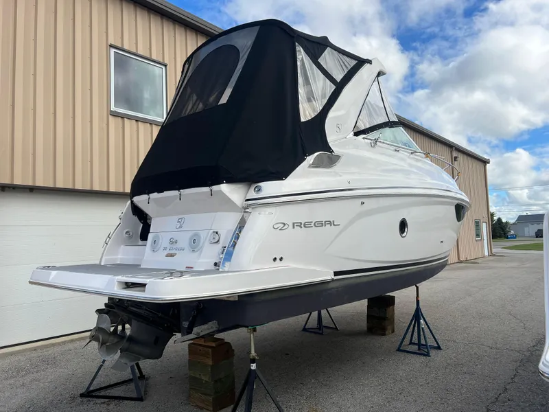 Slide: The Image of 2021 Regal 28 Express boat on stands, white hull, black canopy, outdoor storage. - 3