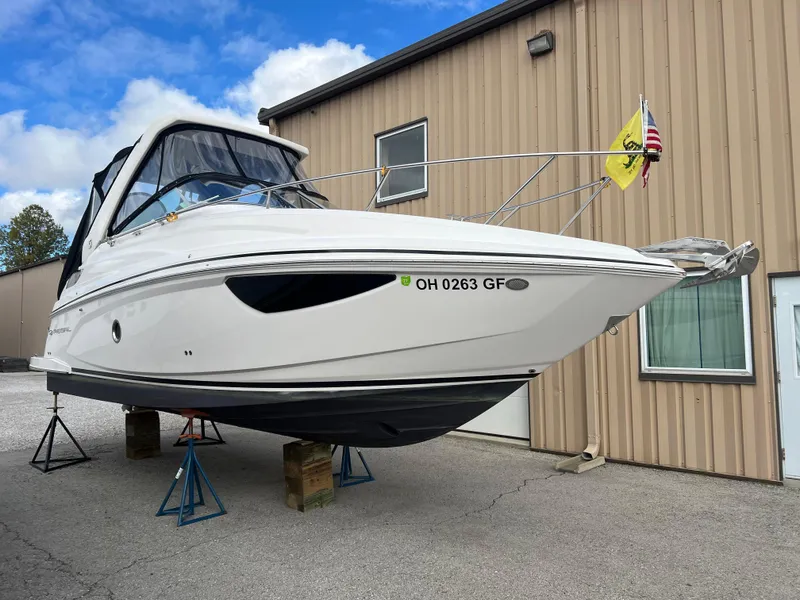 Slide: The Image of 2021 Regal 28 Express boat on stands, near a beige building. - 4