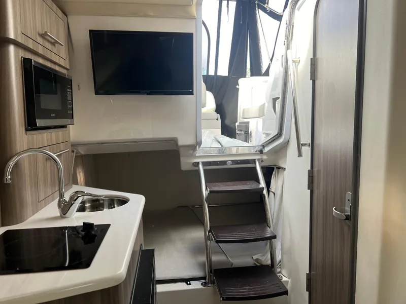 Slide: The Image of Interior of 2021 Regal 28 Express boat with kitchenette, TV, and stairs to deck. - 5