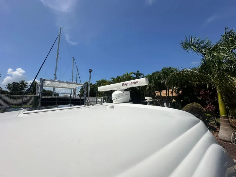 Slide: The Image of 2005 Sea Ray 420 Sundancer with Raymarine radar, docked near palm trees under clear sky. - 13