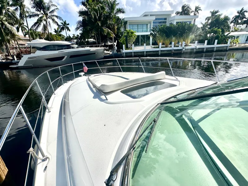 Slide: The Image of 2005 Sea Ray 420 Sundancer yacht docked by waterfront homes, surrounded by palm trees. - 7