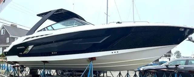 Slide: The Image of 2016 Cruisers Sport Series 328CX boat on stands, black and white exterior, docked outdoors. - 0