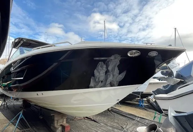 Slide: The Image of 2016 Cruisers Sport Series 328CX boat on dry dock under a cloudy sky. - 1