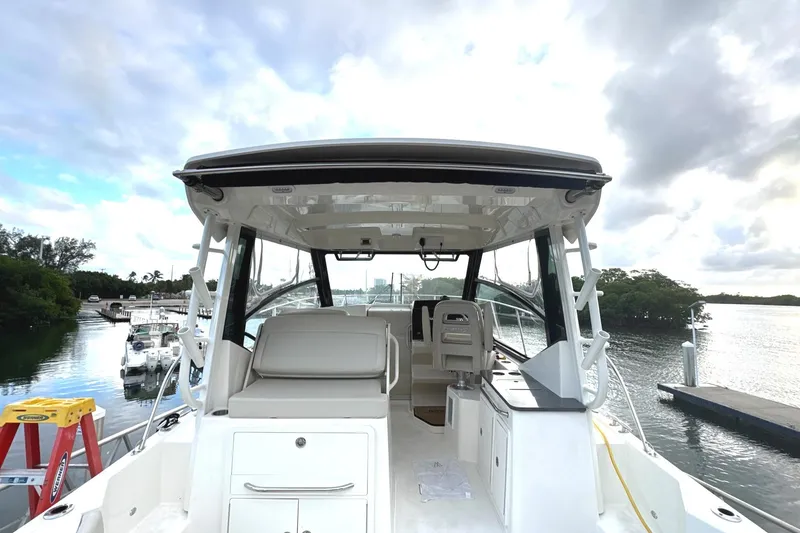Slide: The Image of 2023 Boston Whaler 325 Conquest boat docked by a serene waterfront. - 28