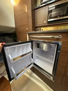 Slide: The Image of 2023 Boston Whaler 325 Conquest interior with open mini fridge and microwave. - 46