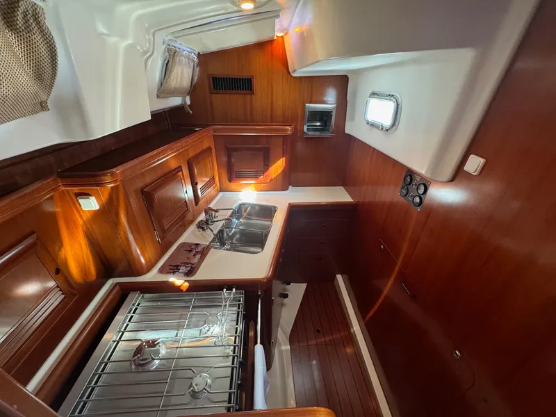 Slide: The Image of Interior of 2002 Beneteau 50 yacht, featuring a well-equipped kitchen with wooden cabinetry. - 31