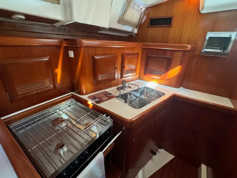Slide: The Image of Beneteau 50 yacht kitchen, 2002 model, featuring wood cabinetry, stove, and double sink. - 32