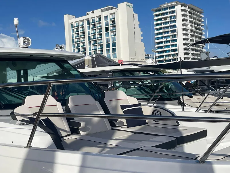 Slide: The Image of 2025 Jeanneau Leader 12.5 WA yacht with modern seating, docked near tall buildings. - 2