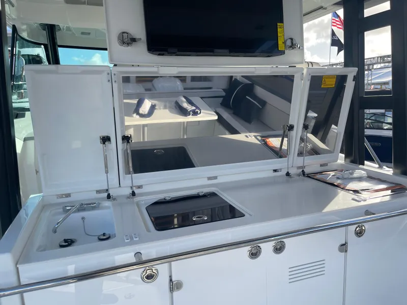 Slide: The Image of 2025 Jeanneau Leader 12.5 WA boat interior with kitchenette and seating area. - 6