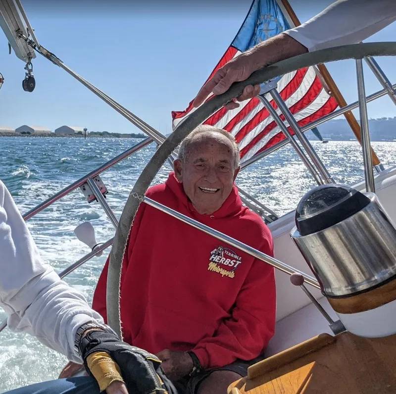 Slide: The Image of Man steering 1980 Skye 51 Ketch sailboat with American flag in background. - 43
