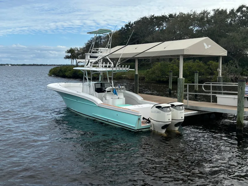 Slide: The Image of 2006 Buddy Davis 34 Center Console boat docked by a pier on a calm lake. - 3