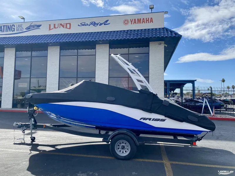 Slide: The Image of 2024 Yamaha AR195 boat on trailer outside dealership, covered and ready for transport. - 2