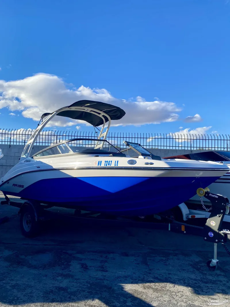 Slide: The Image of 2024 Yamaha AR195 boat with blue hull and canopy, parked outdoors under a clear sky. - 4