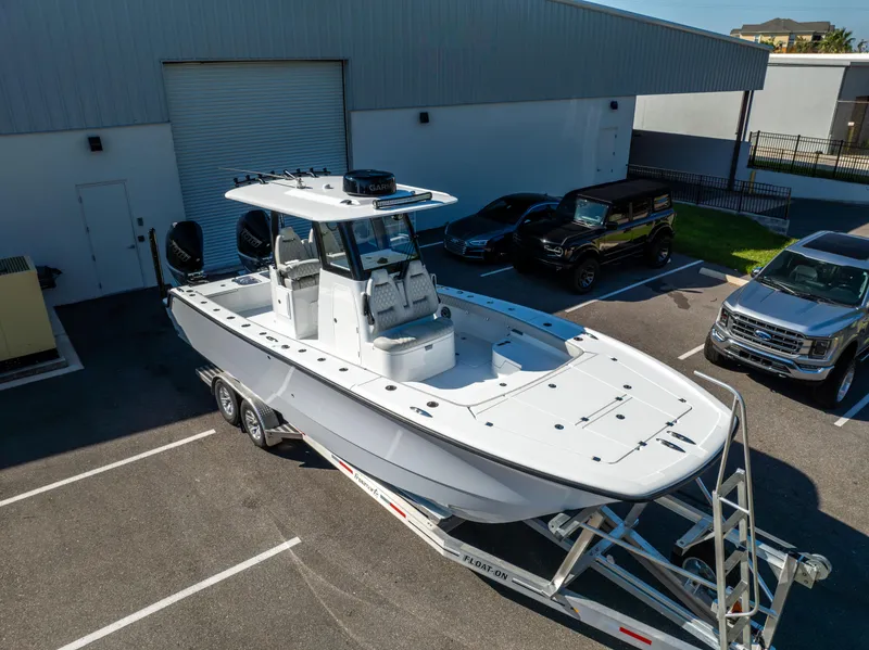 Slide: The Image of 2024 Freeman 28 boat on trailer in parking lot, near vehicles and building. - 12