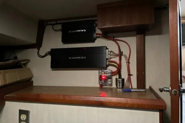 Slide: The Image of Electrical setup inside a 1977 Uniflite Bridge Cruiser boat, featuring amplifiers and wiring. - 24