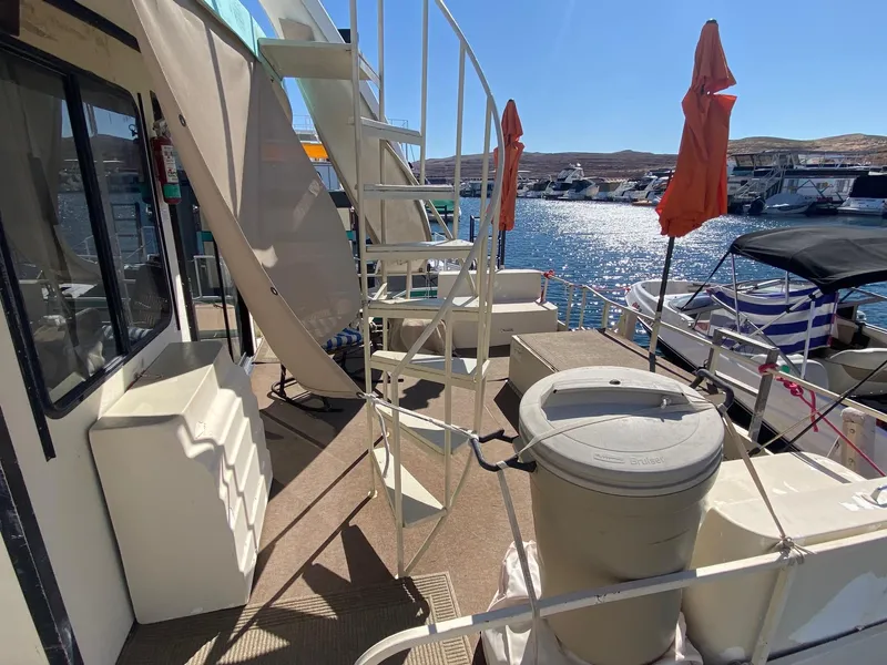 Slide: The Image of 1988 Boatel Hercules houseboat deck with spiral staircase, docked at marina under clear blue sky. - 12